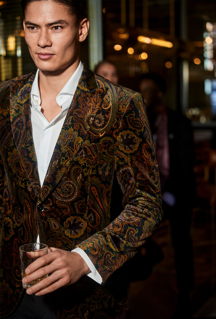 Young man with brown hair in striking velvet jacket with paisley pattern 